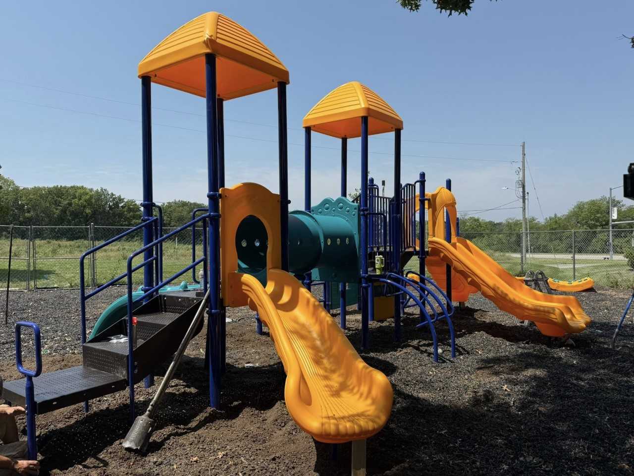 Outdoor playground installation with bright yellow slides, climbing features, and connecting tunnels, installed in an open play area to support active and imaginative play.