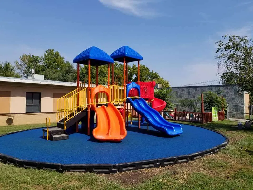 Colorful playground equipment with multiple slides and safety surfacing in an outdoor park, designed for safe and engaging play for children